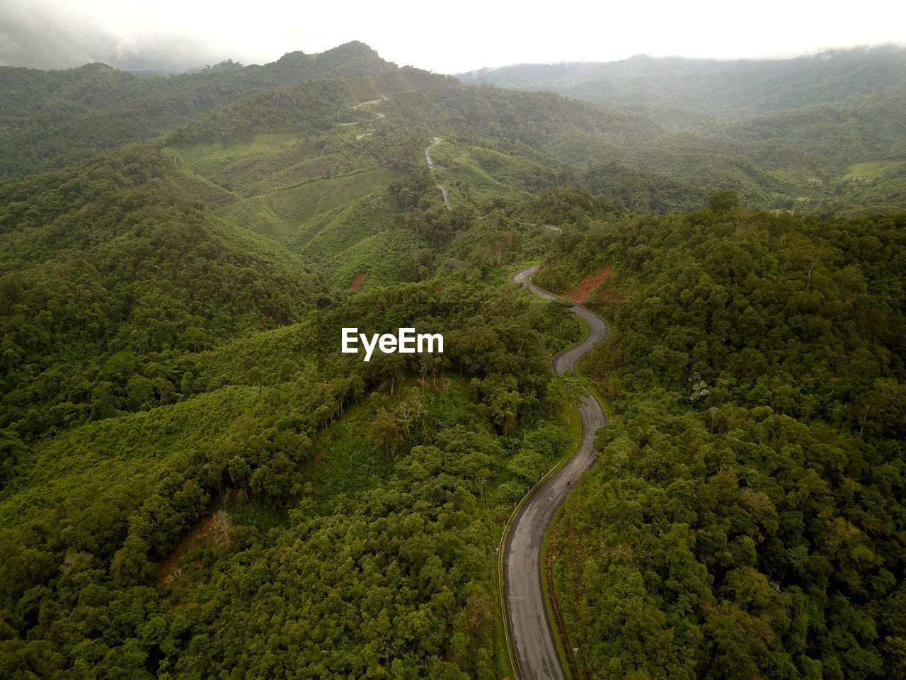 Countryside road passing through the lush green tropical rain forest mountain landscape