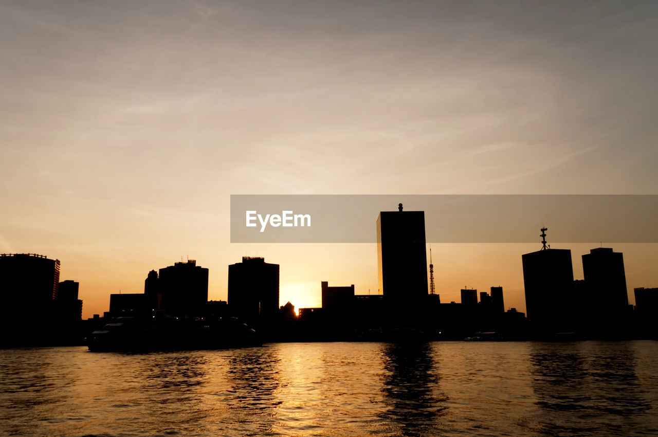 Sunset over river with buildings in background