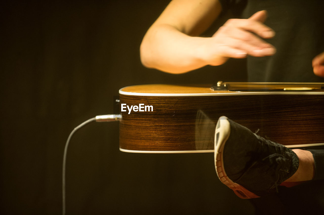 Low section of man playing guitar