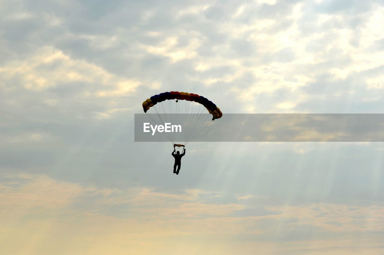 Person paragliding against cloudy sky