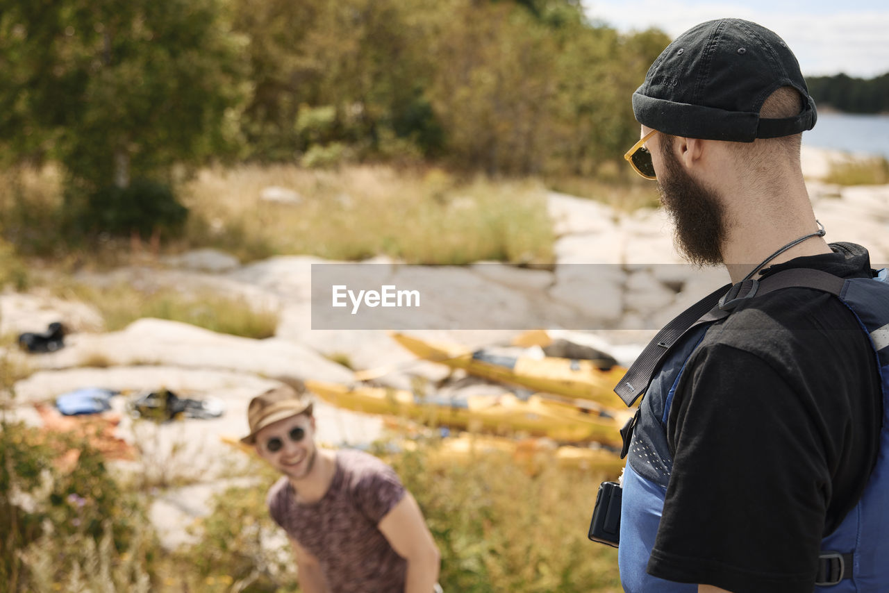 Men talking at coast, kayaks in background