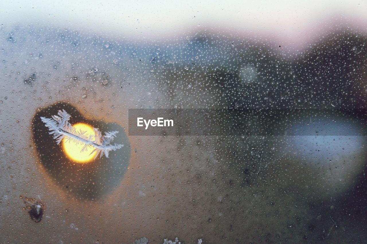 Snowflakes and sun seen through condensed window during winter