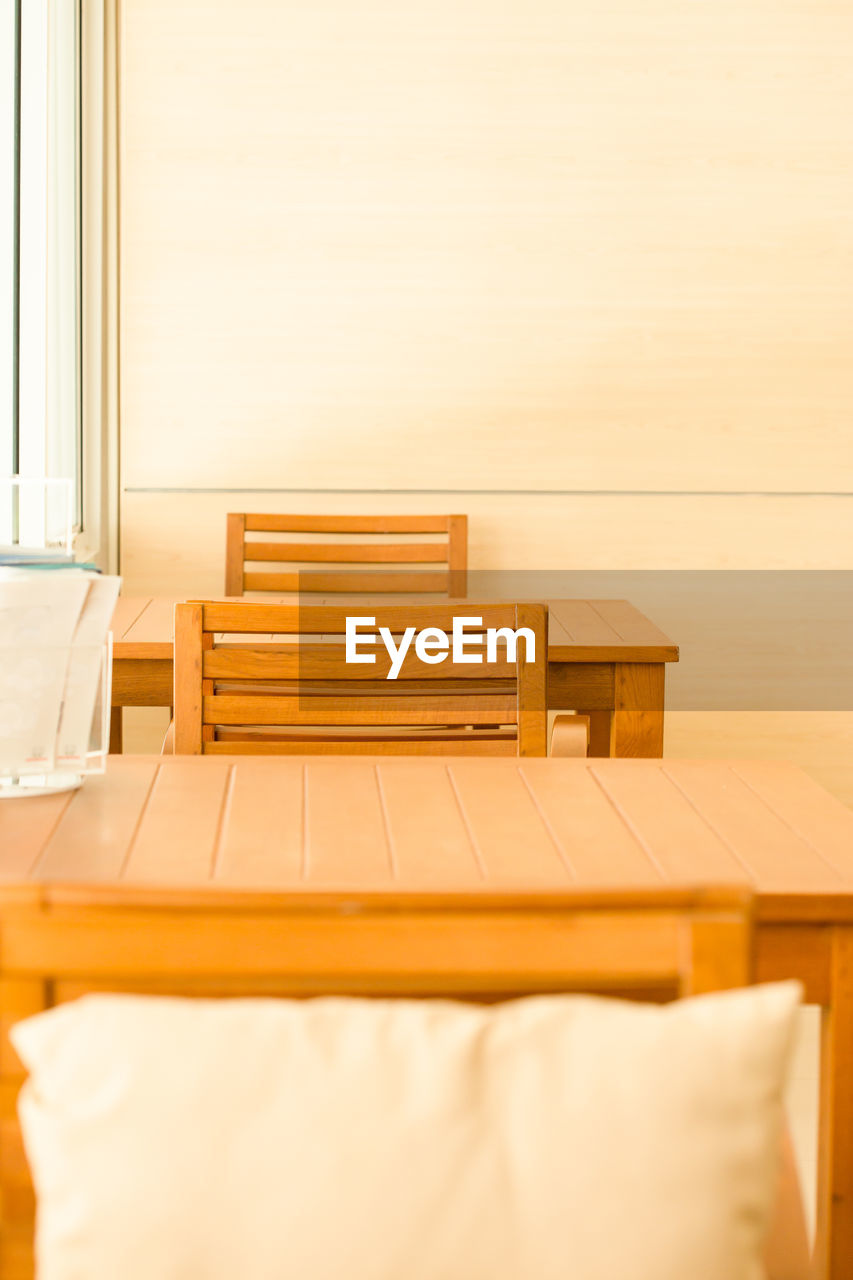 EMPTY CHAIR AND TABLE ON BED AGAINST WALL