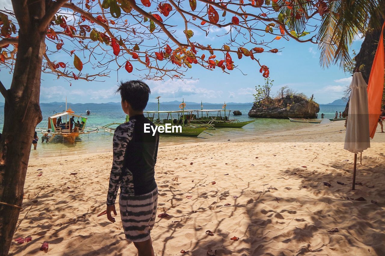 Man standing on sand while looking at sea