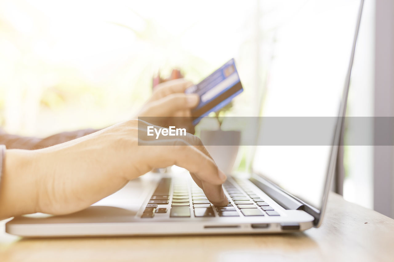 MIDSECTION OF MAN USING LAPTOP