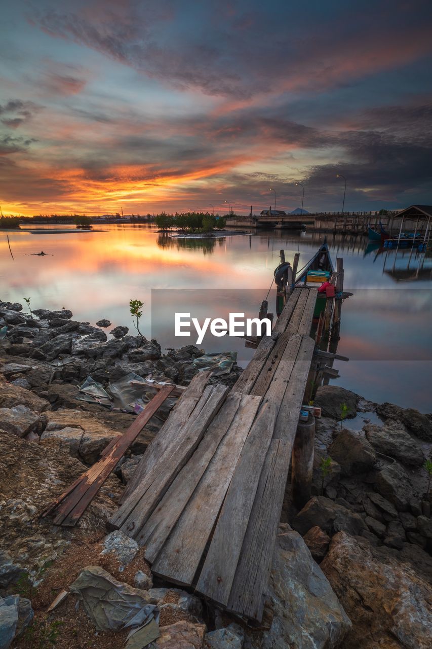 Pier over lake against sky during sunset