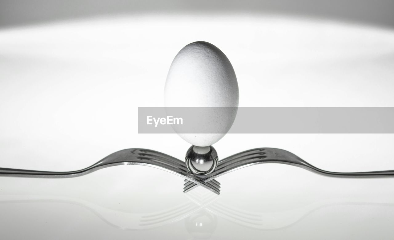Close-up of egg on forks against white background