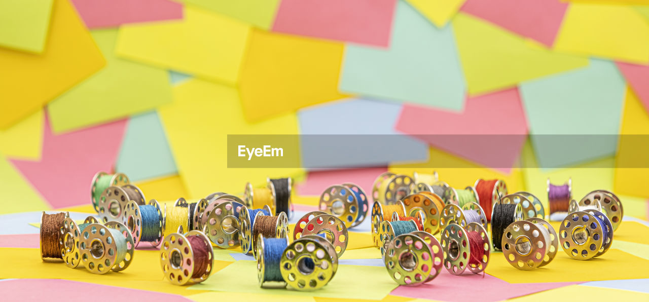Metal spools with multicolored thread for sewing machine on a table with colored paper sticky notes