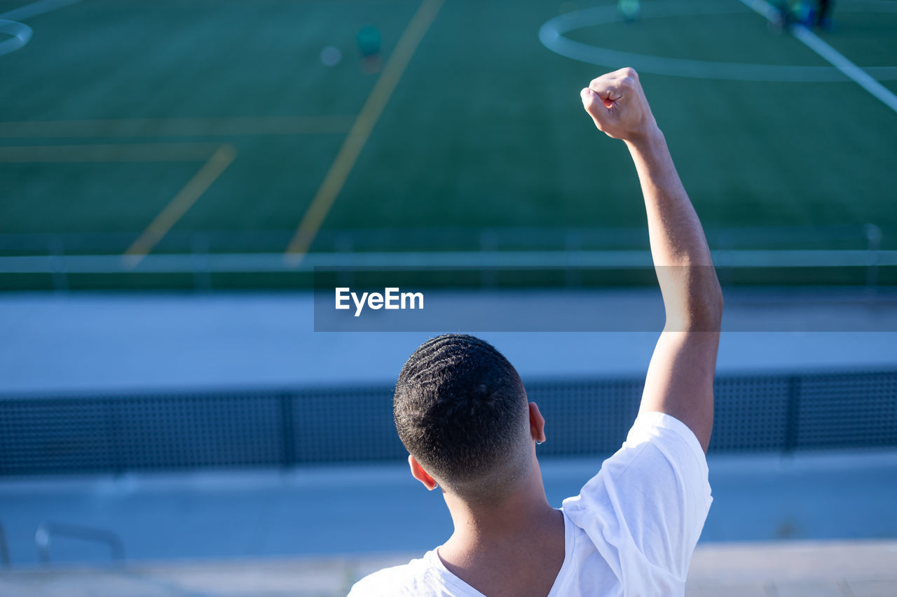 rear view of man playing tennis at court