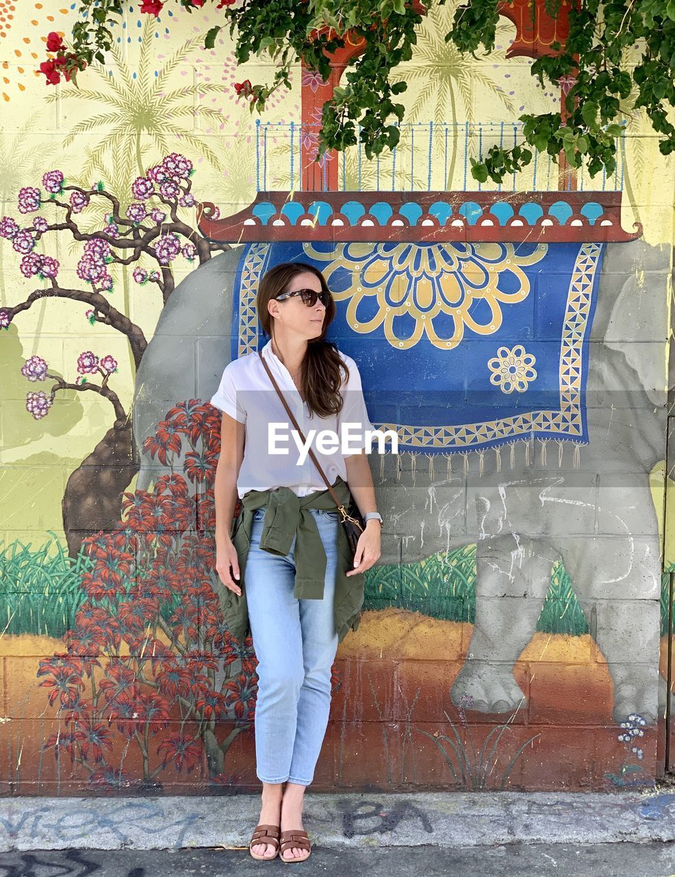 Woman looking away while standing against wall