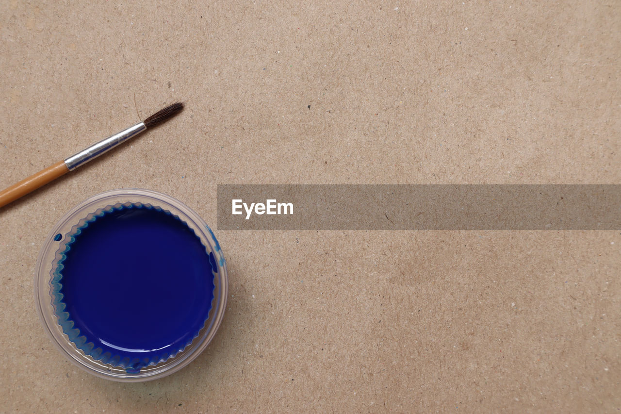 Blue watercolor, ready to use, plastic cups and brushes on the background, brown paper