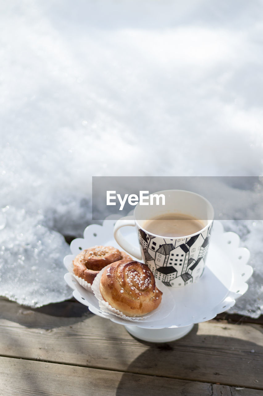 CLOSE-UP OF COFFEE CUP WITH BREAD ON TABLE