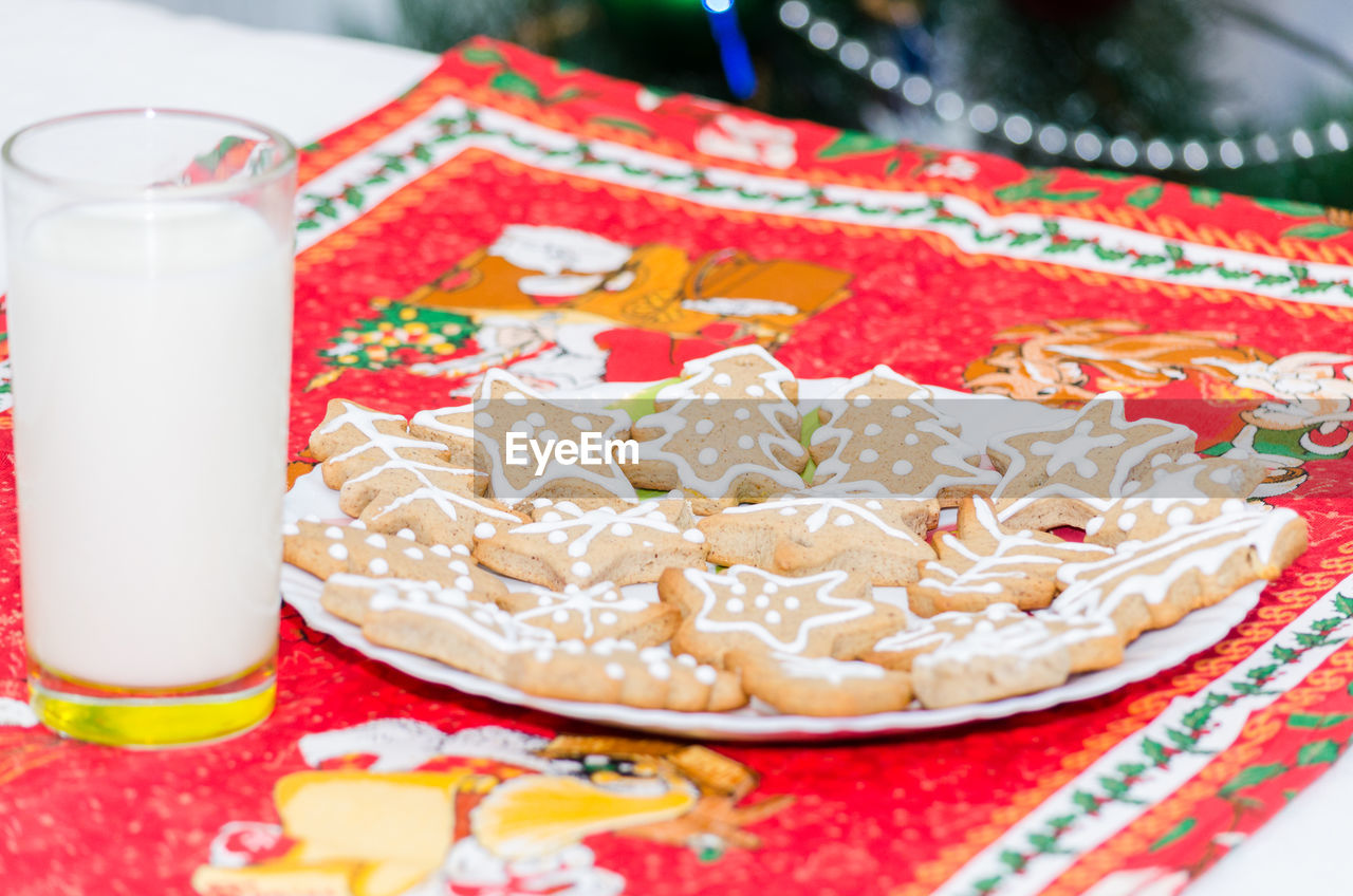 Close-up of milk glass by gingerbread cookies in plate on table