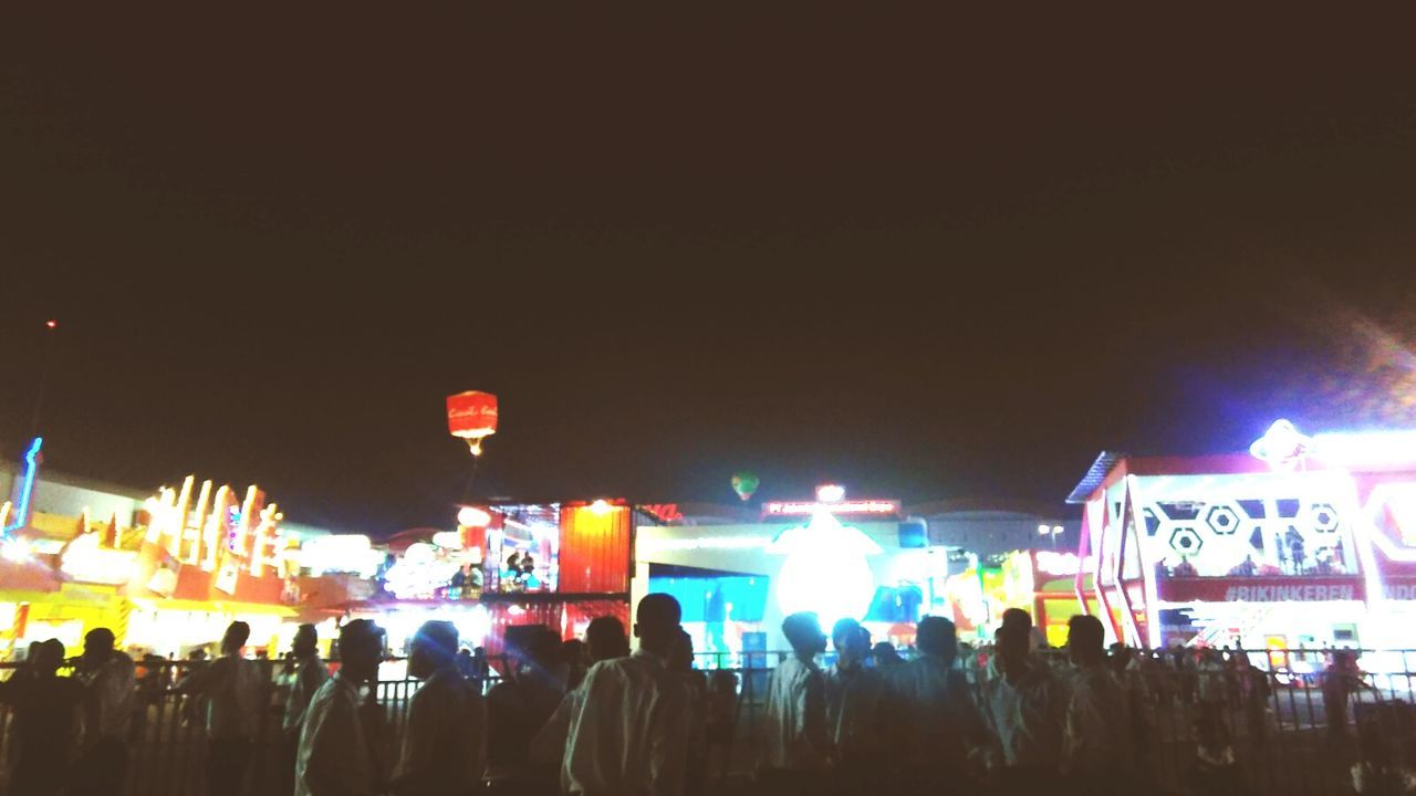 PEOPLE IN AMUSEMENT PARK AT NIGHT