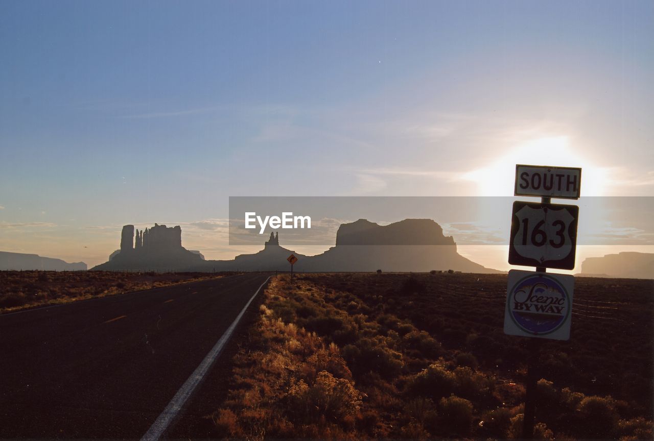 horizon, sky, road, sign, morning, nature, dawn, sunrise, landscape, transportation, communication, mountain, road sign, no people, travel, environment, land, scenics - nature, cloud, guidance, sunlight, travel destinations, desert, outdoors, symbol, text, beauty in nature, city, copy space