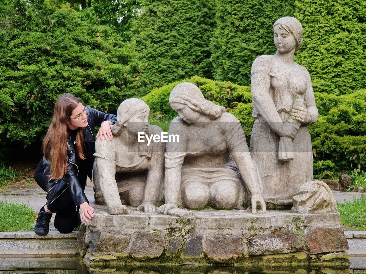 Sculpture of washng women in pond with posing woman