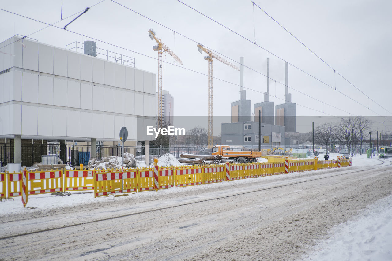 Vehicles on road against sky in winter