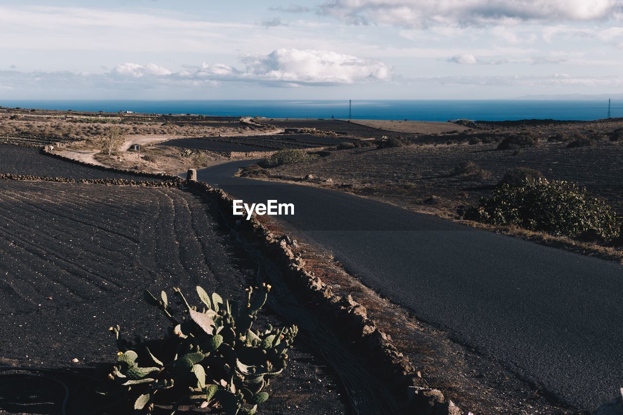 Scenic view of road by sea against sky