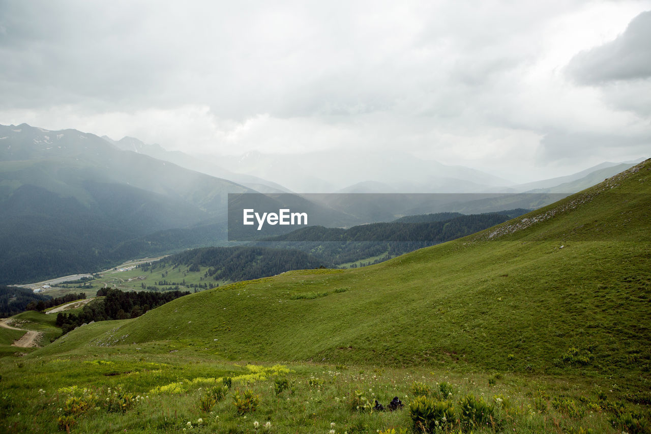 Green slope of a high mountain during a thunderstorm with clouds in the sky