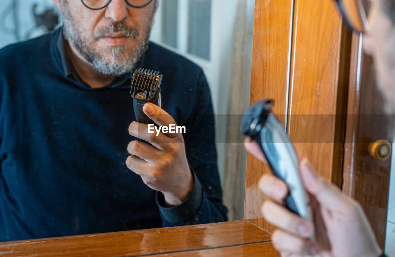 Man at the mirror watching an hair clipper in quarantine