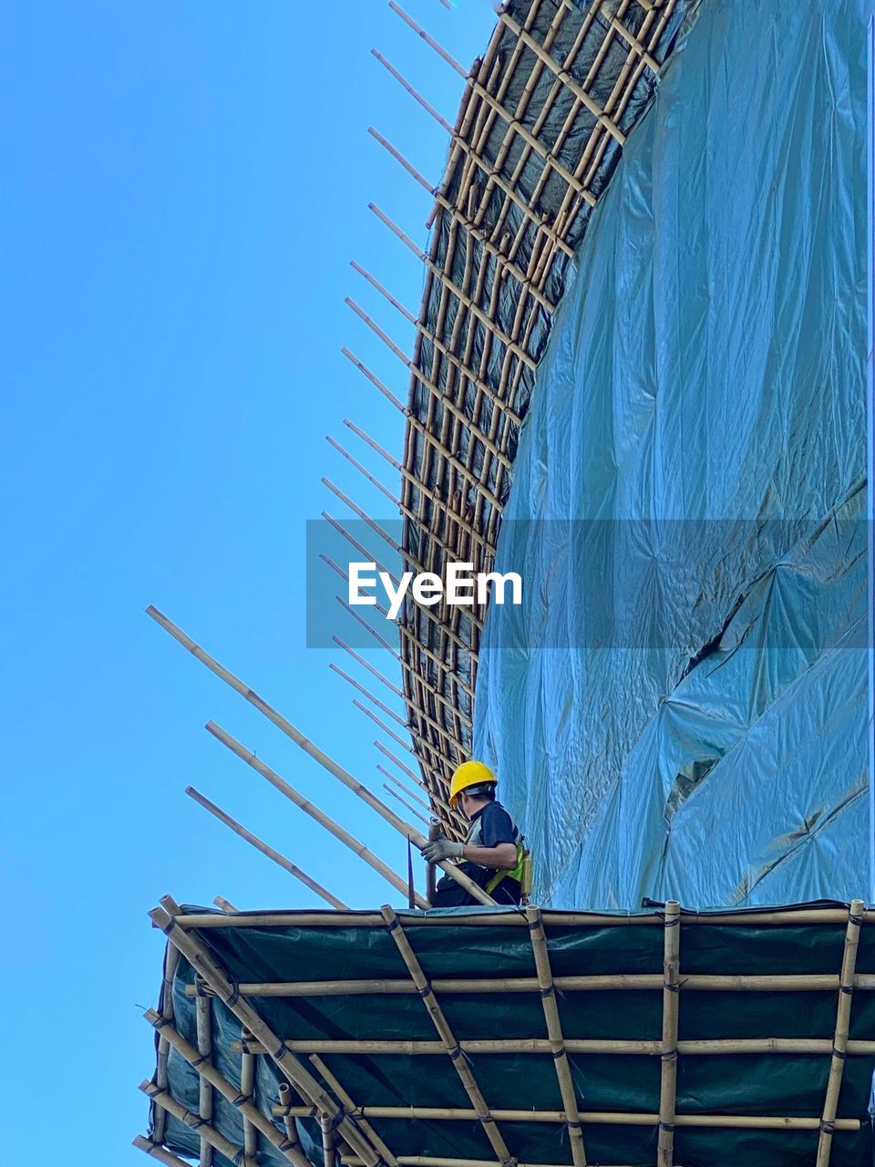 Low angle view of construction site against clear blue sky