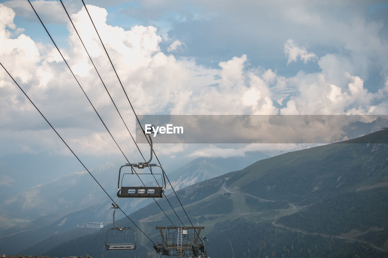 LOW ANGLE VIEW OF CABLES AGAINST MOUNTAIN RANGE