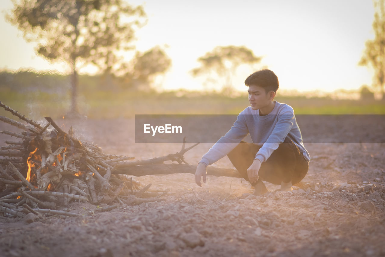 A young man in winter was sitting by the fire to alleviate the cold, lifestyle thailand.