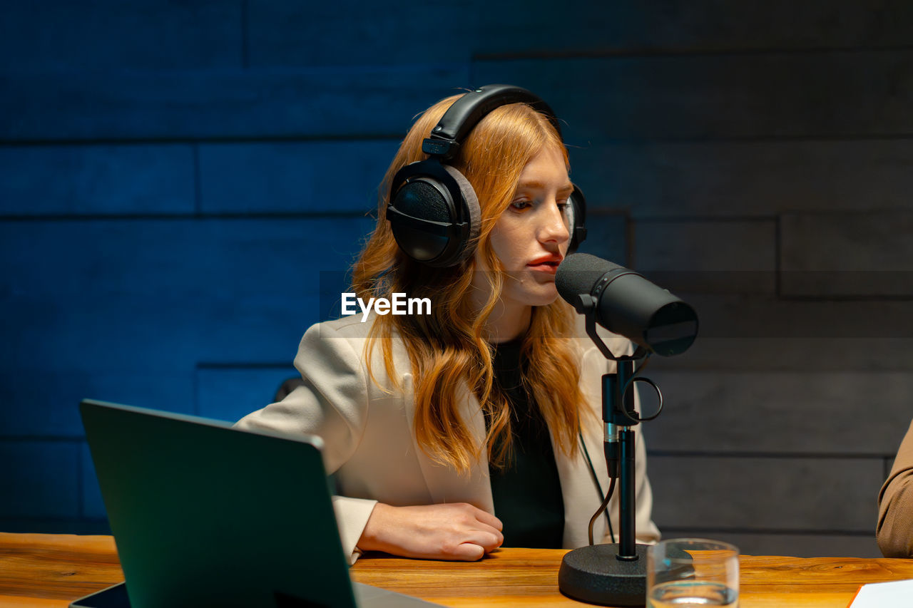A woman with headphones in front of a microphone. at podcast studio