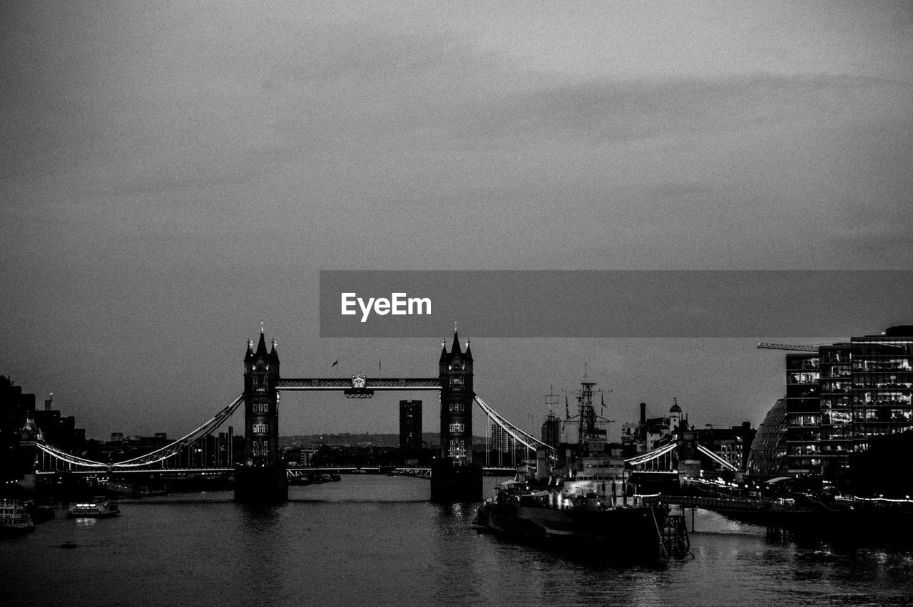 Tower bridge over river against sky at dusk