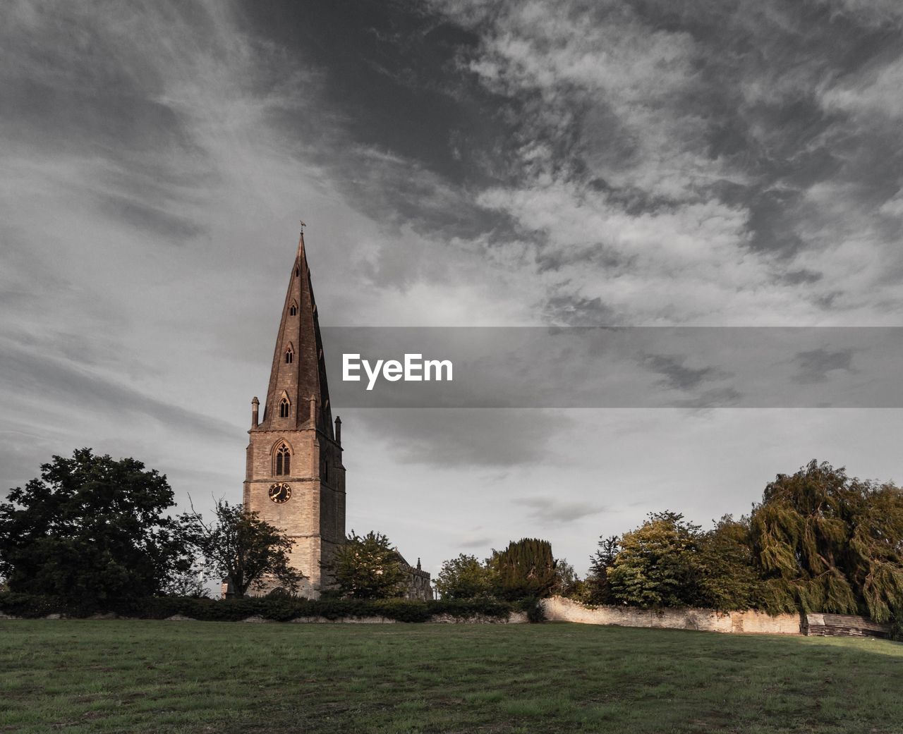 Church tower amidst trees and buildings against sky