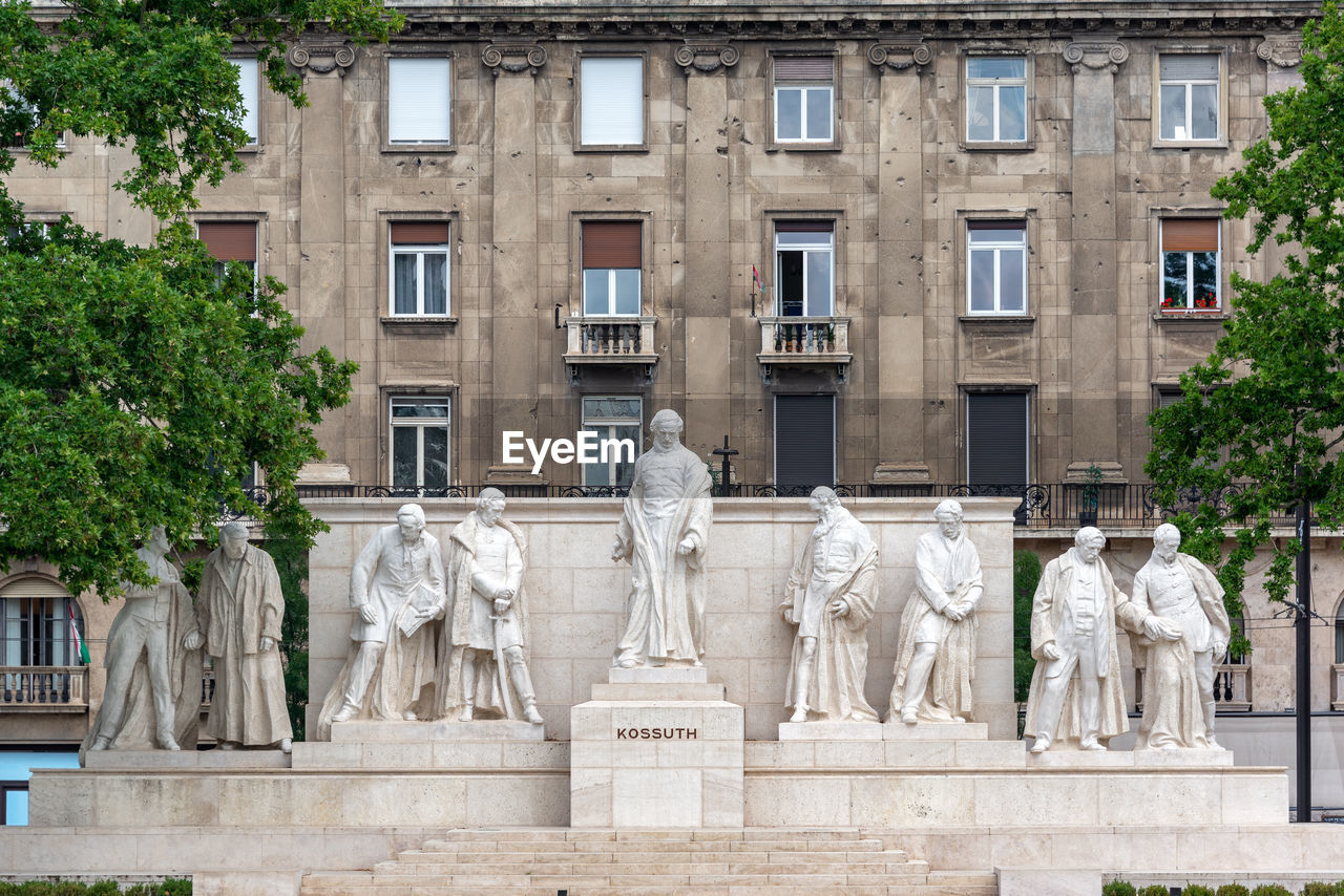 STATUE BY BUILDING AGAINST TREES