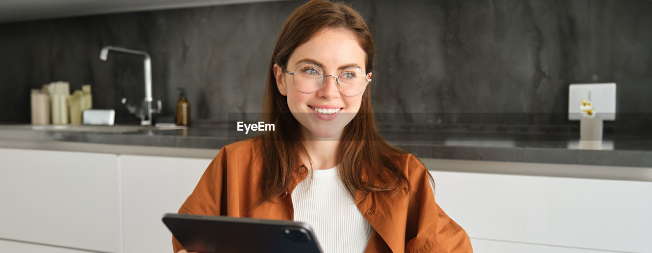 portrait of young woman using mobile phone while sitting on table