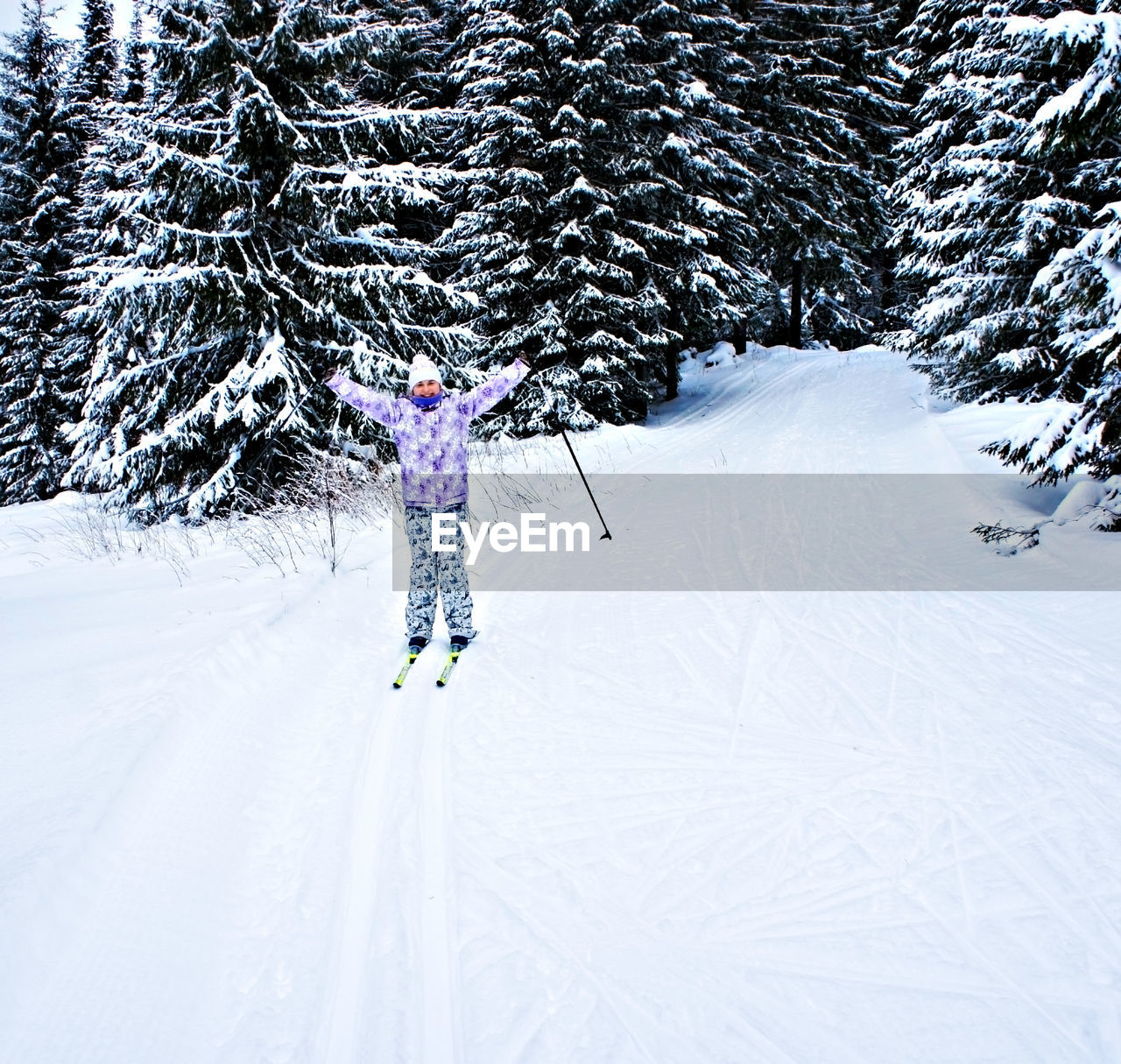 Young happy woman in winter ski clothing skiing in beautiful coniferous fir forest. winter sport