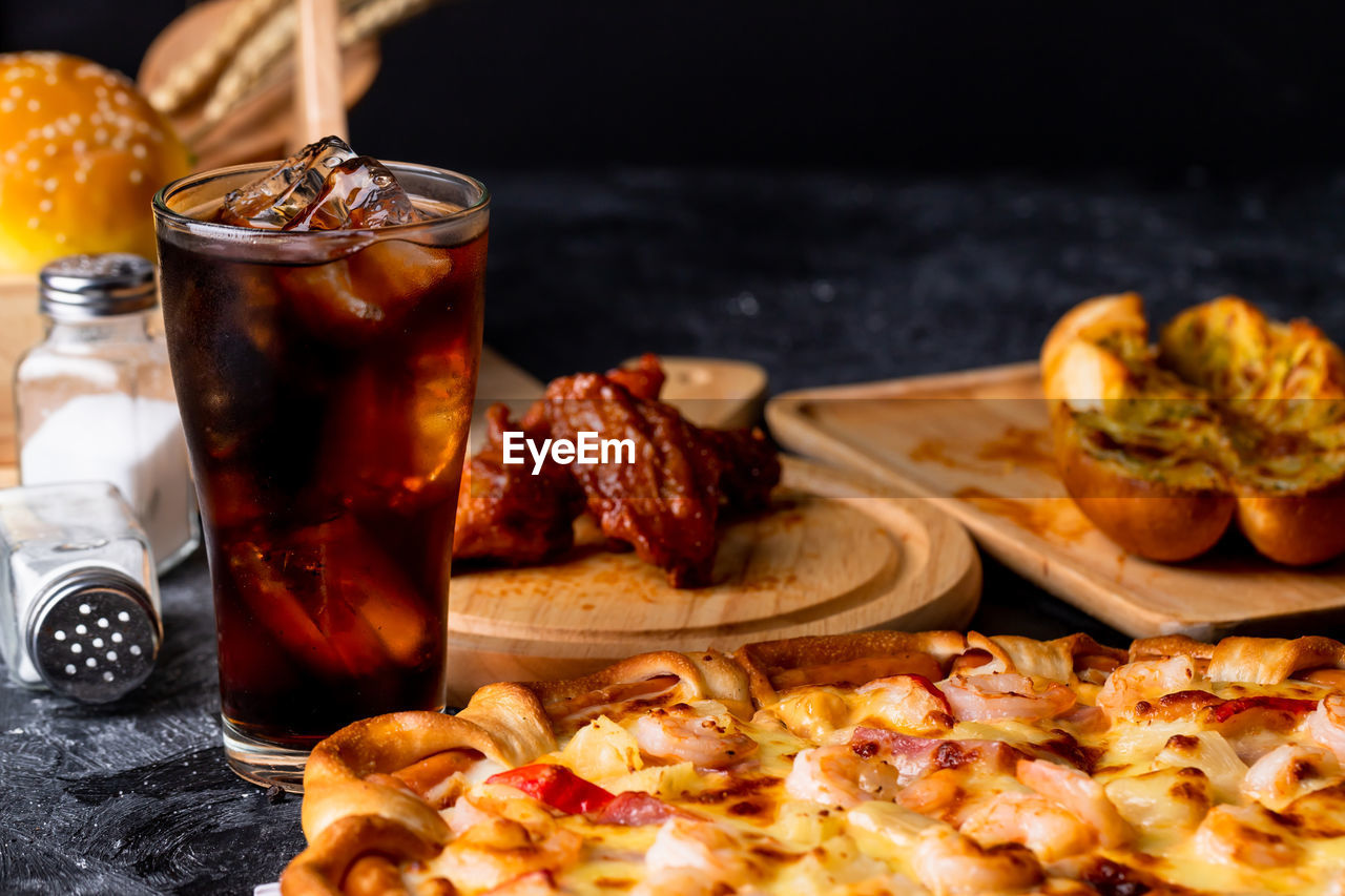 Pizza served with cold drink on the black table