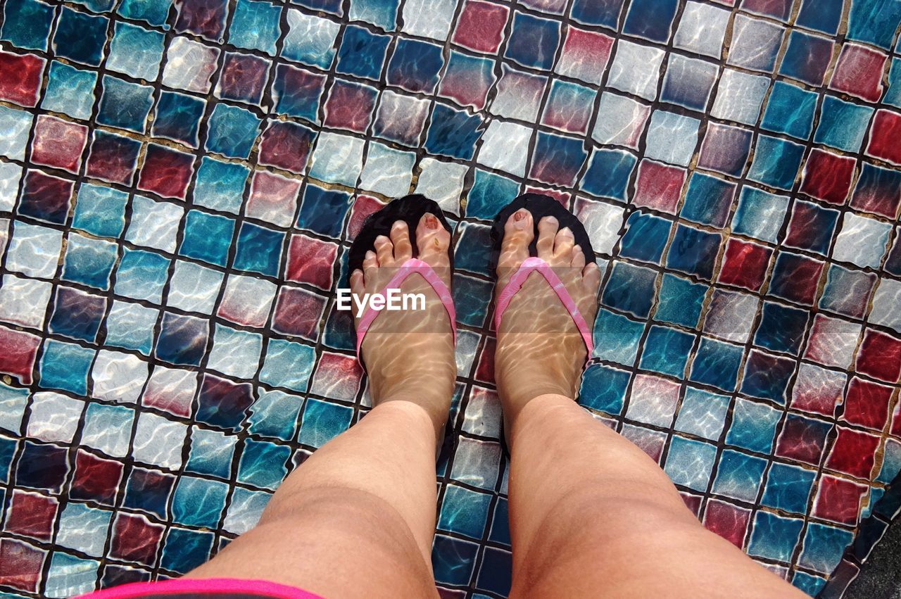 Low section of woman standing in swimming pool