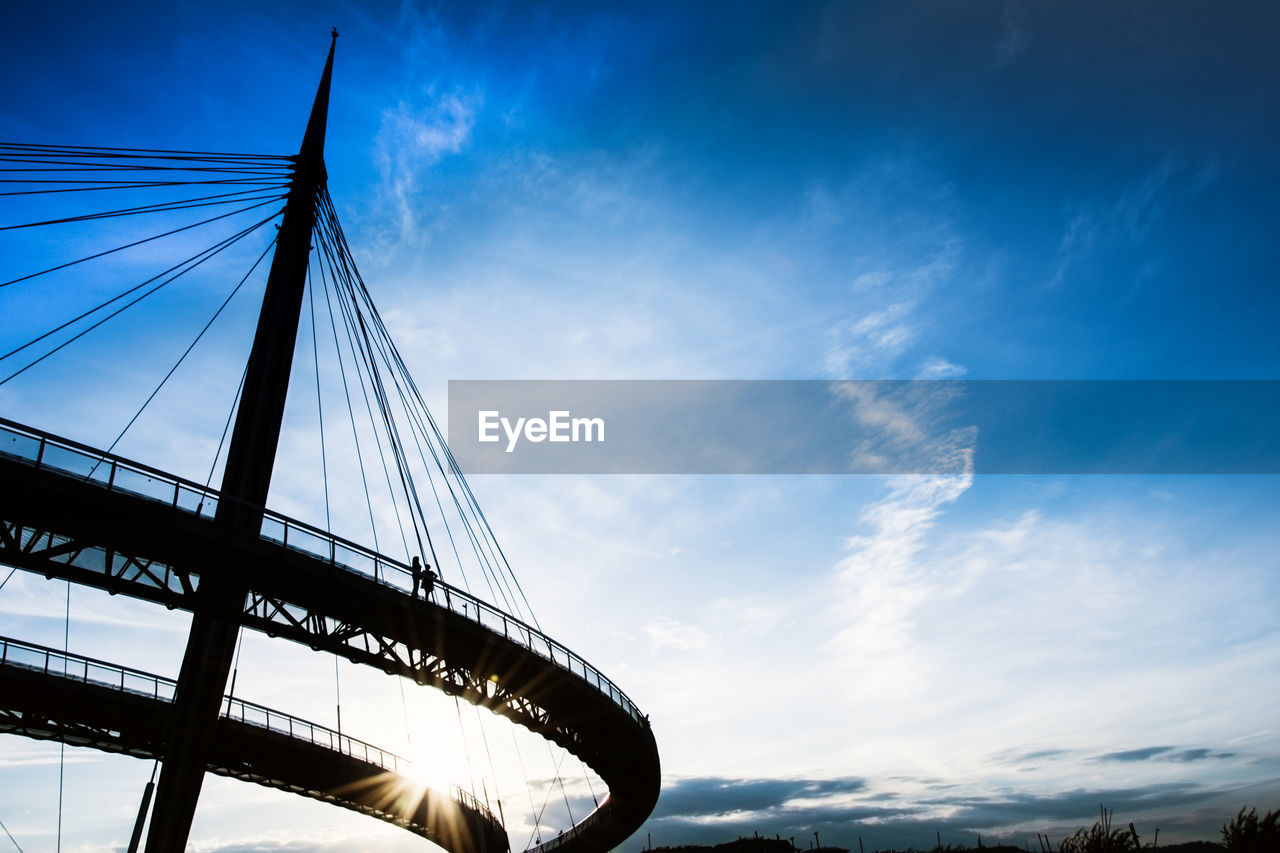 Low angle view of suspension bridge against cloudy sky