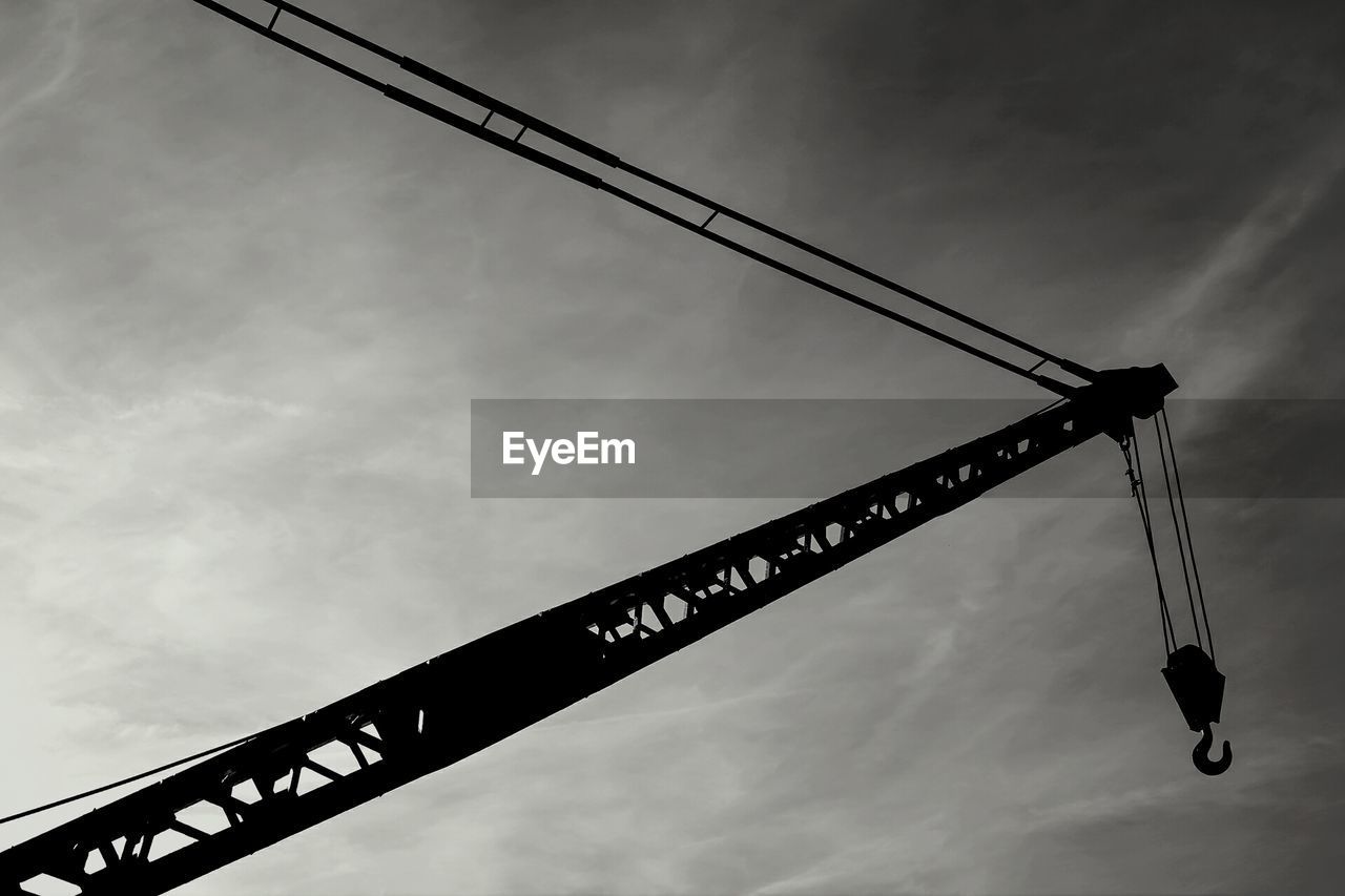 Silhouette crane against sky