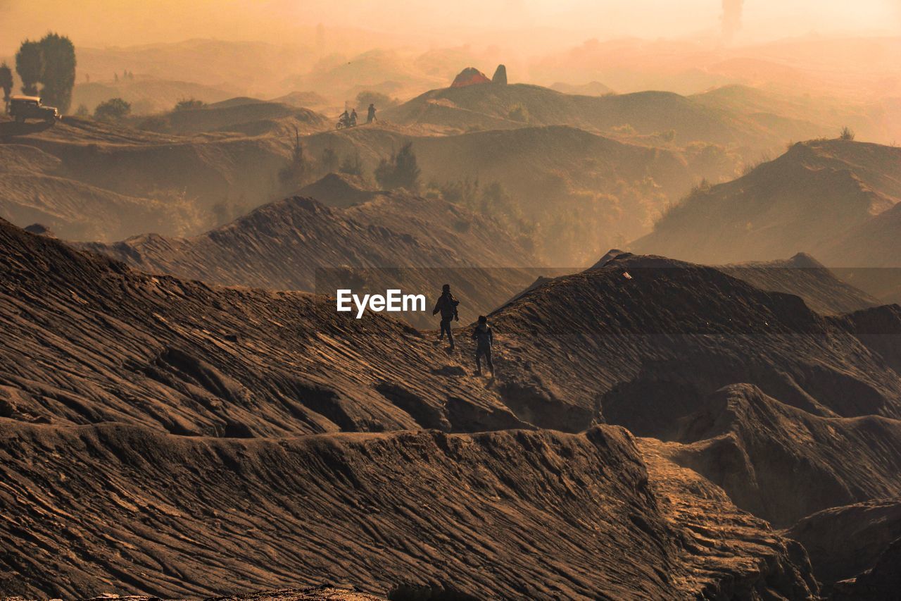 Hikers walking on mountain during sunset