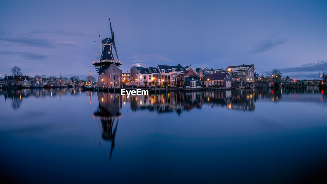 Illuminated windmill adriaan by spaarne river against sky at night