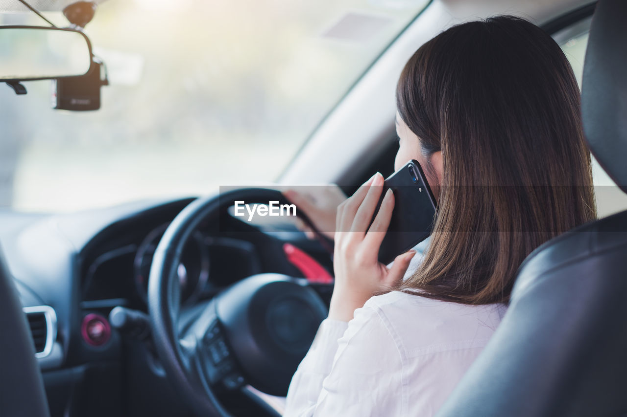 Woman answering smart phone while driving car