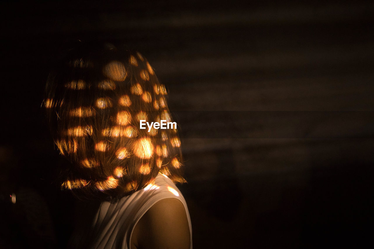 Close-up of woman with sunlight falling on face in darkroom