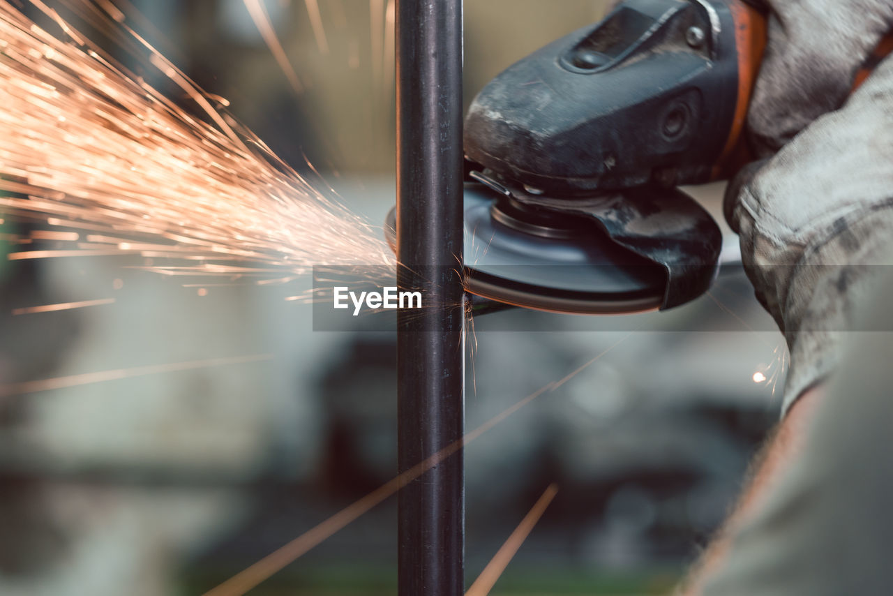 Cropped hand of person grinding metal in workshop