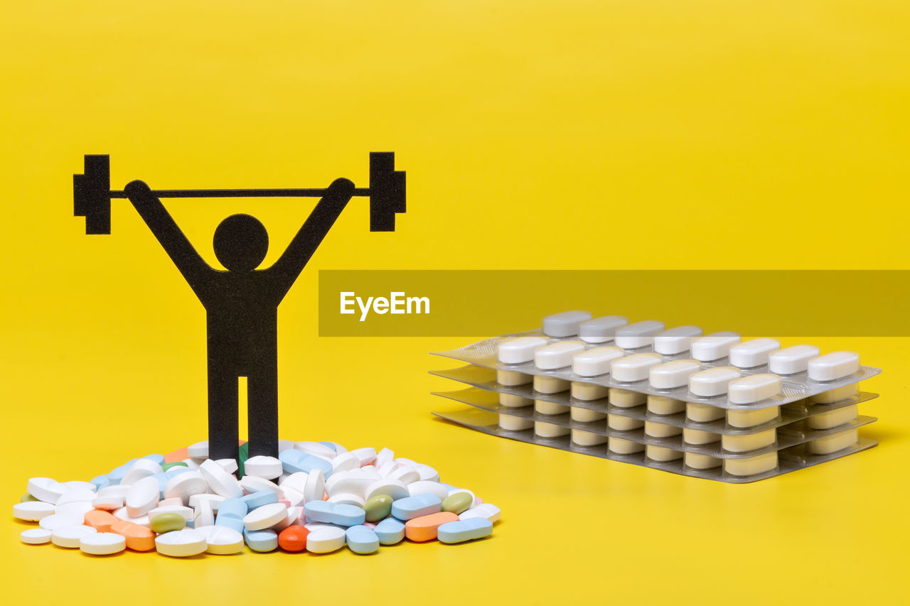 Pills and human representation on yellow background
