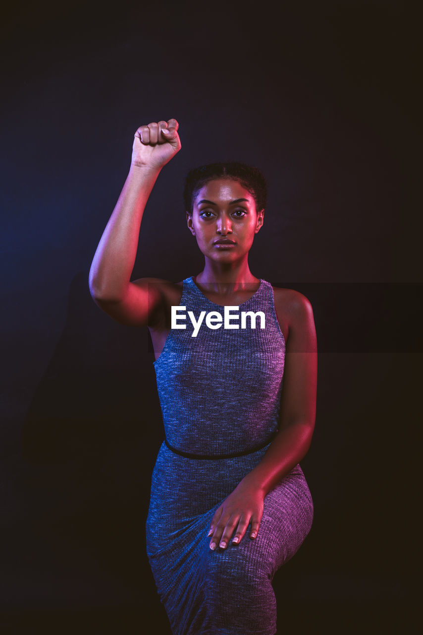 Portrait of woman standing against black background