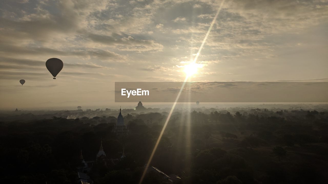 Silhouette hot air balloon flying over landscape against sky during sunset