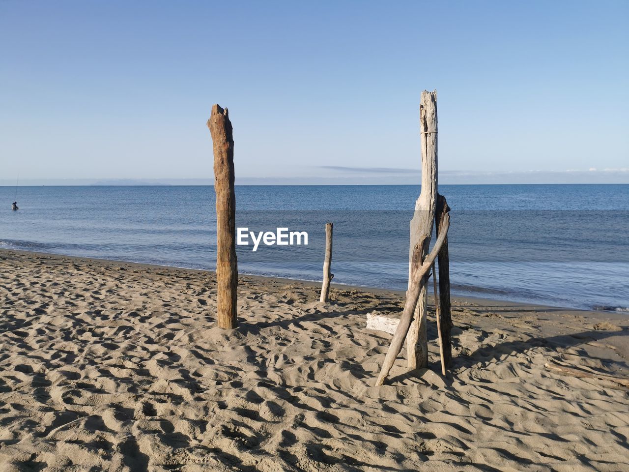 WOODEN POSTS AT BEACH AGAINST CLEAR SKY