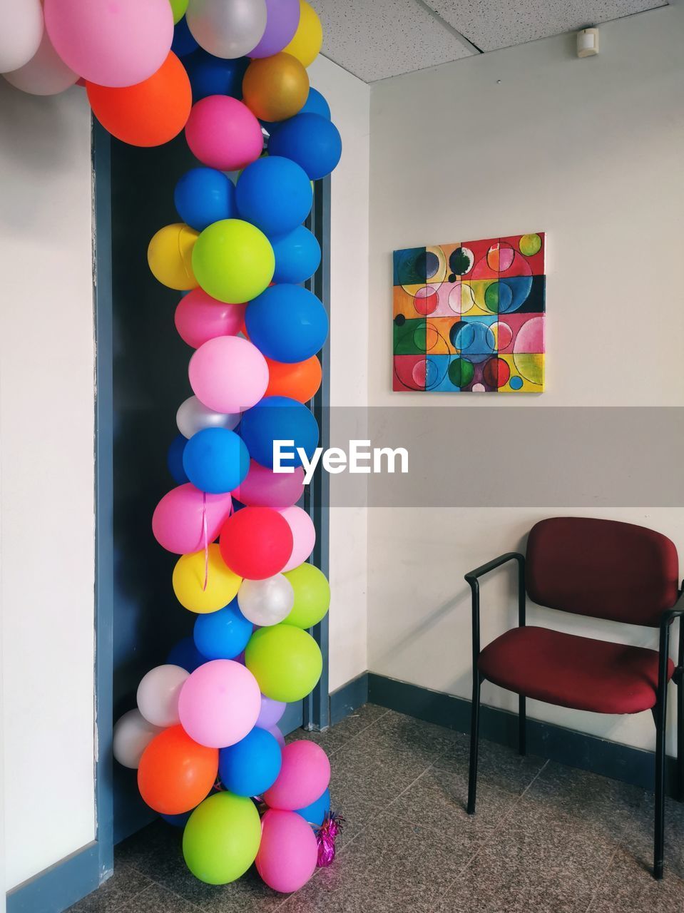 MULTI COLORED BALLOONS ON TABLE AGAINST WALL