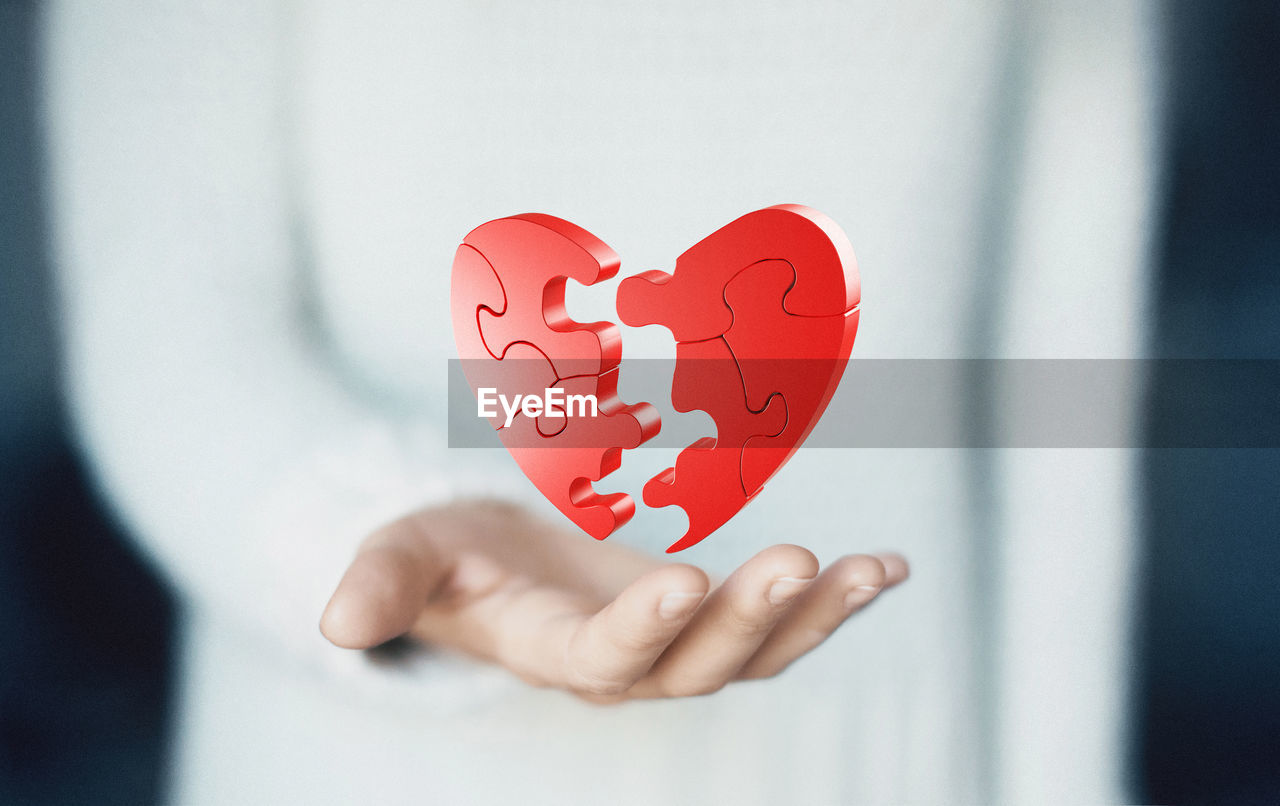 Digital composite image of woman holding heart shape jigsaw puzzle