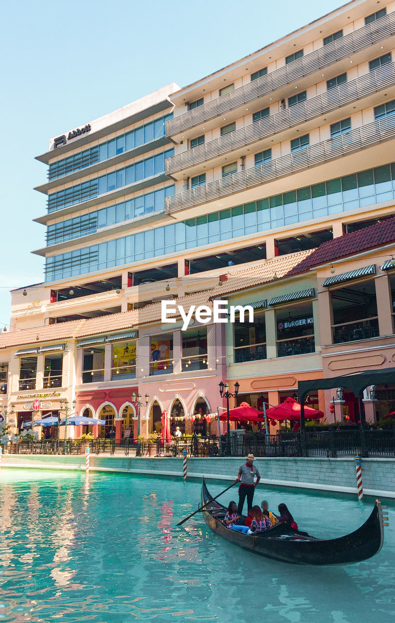 PEOPLE SWIMMING IN POOL AGAINST BUILDINGS