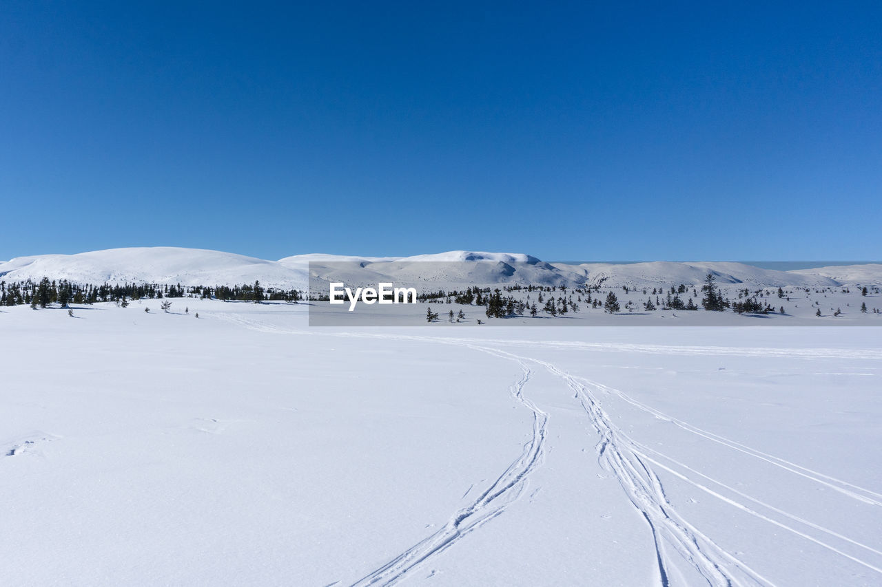 Scenic view of snow covered landscape against clear blue sky